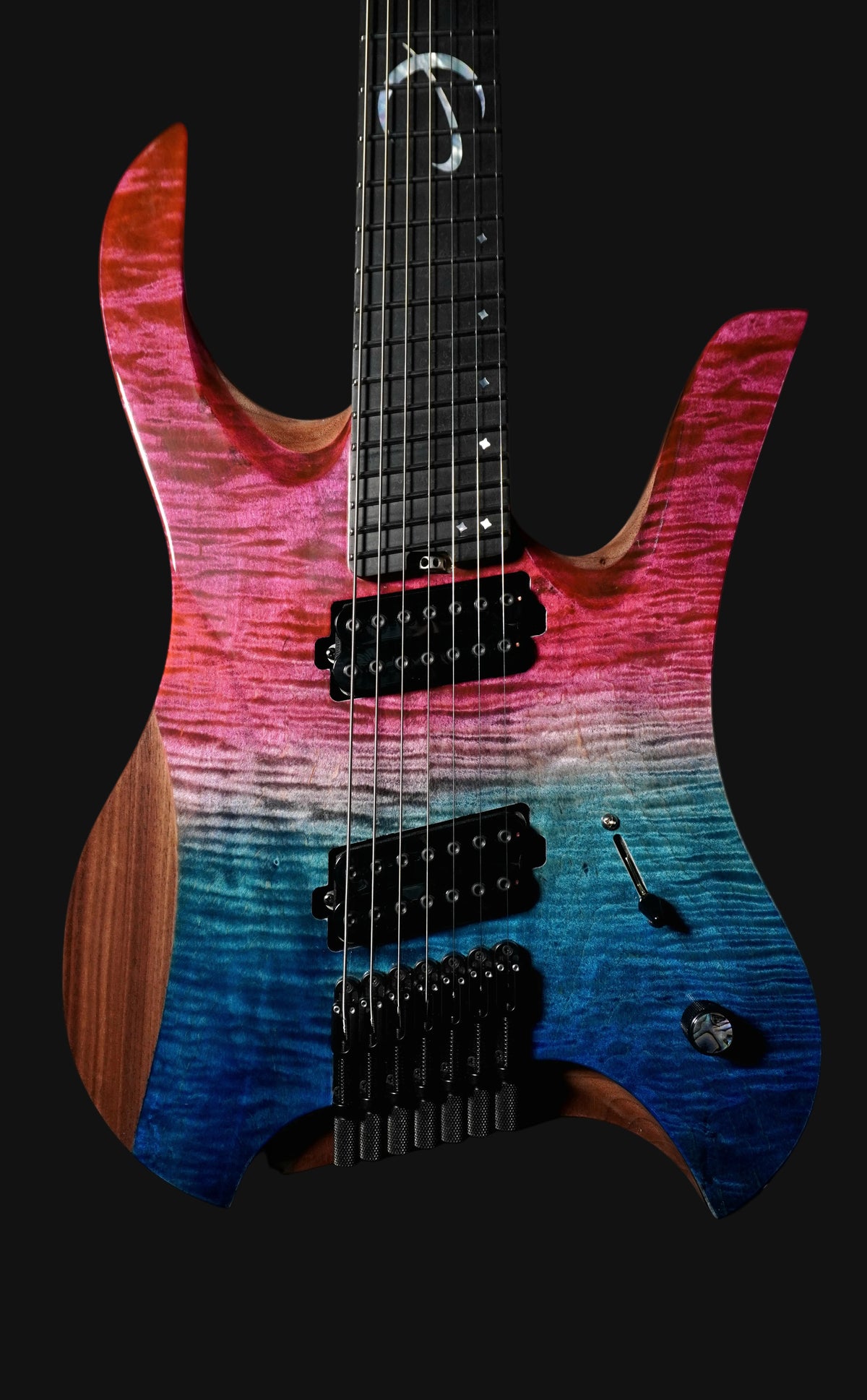 A headless, seven-string electric guitar with a double cutaway body, featuring a darkened mars seafoam finish, birdseye maple fingerboard with mother of pearl inlays, and black hardware.